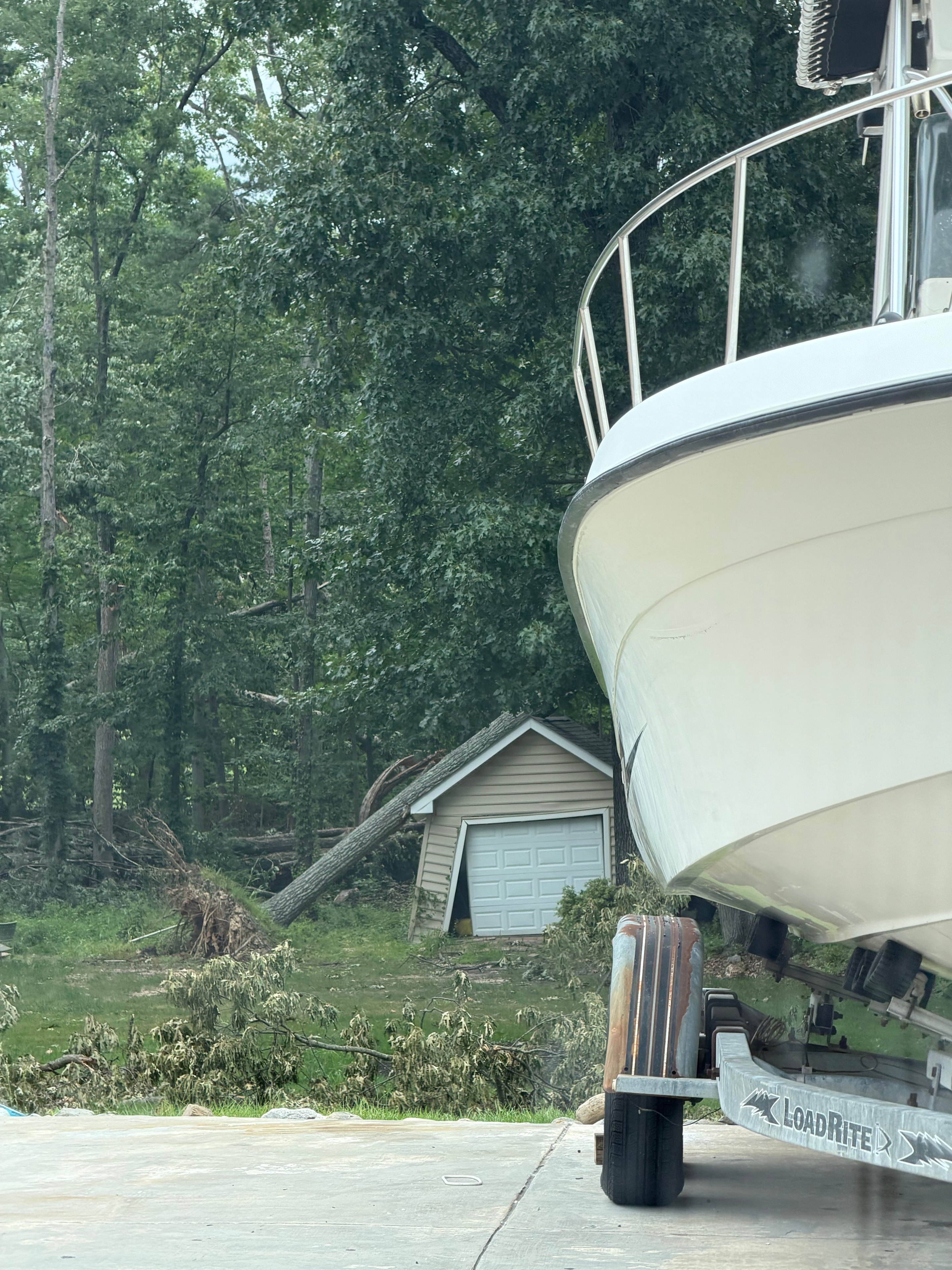 Arundel Tree Service crane lifting large storm-damaged tree over Maryland residential home — professional emergency tree removal