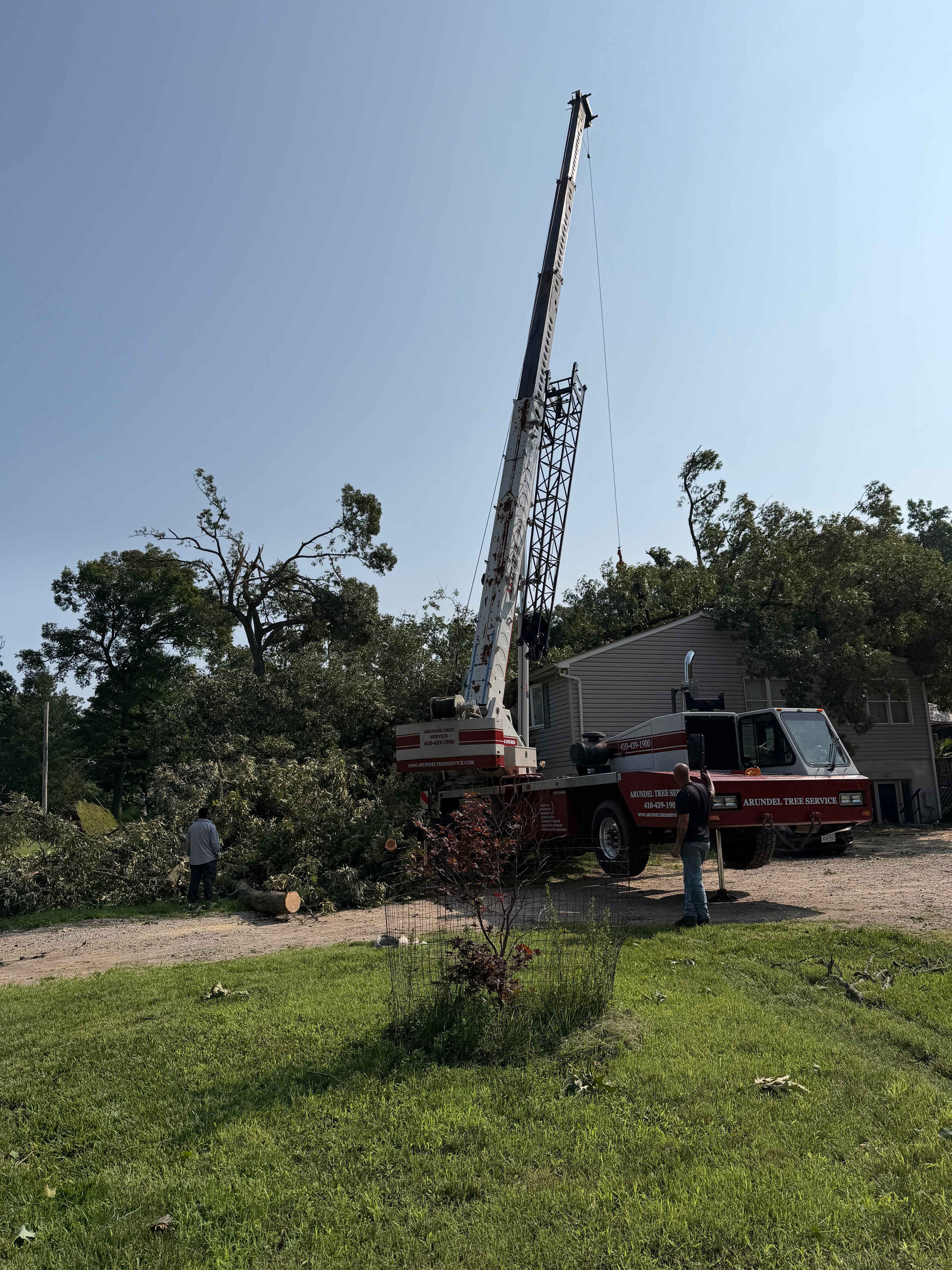 Arundel Tree Service crane truck with extended boom at storm damage site — emergency tree removal Maryland